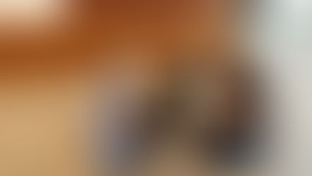 A dog places they're paw in the hands of a veterinarian while the dog's owner holds the dog. 