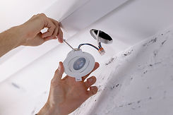 electrician installing recessed lamp in drywall ceiling. led lighting.jpg