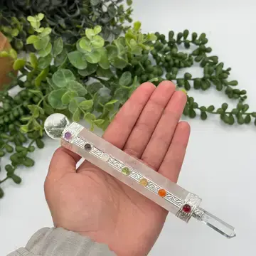 Hand holding a crystal wand with colorful stones and a clear point.