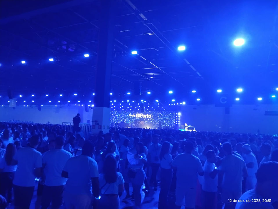 Imagem aberta de um espaço da festa da Porto Seguro, com luz predominantemente azul.