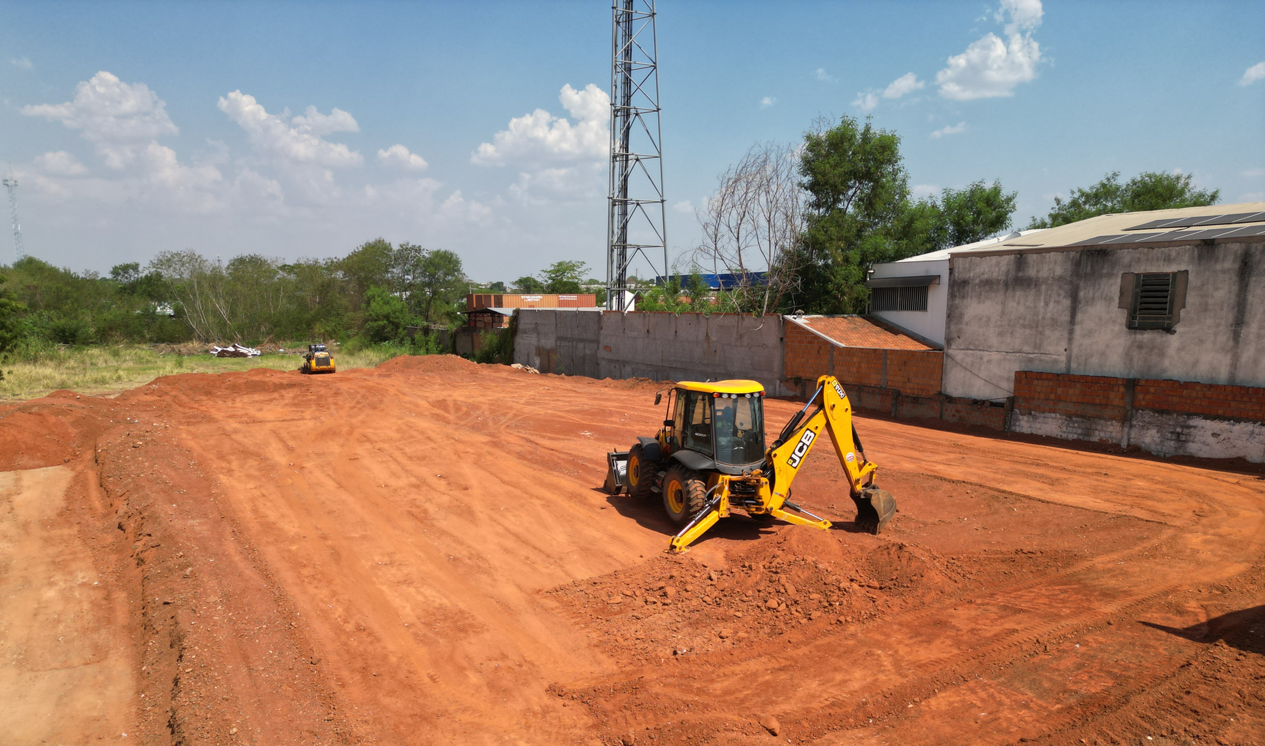 Minicarregadeira e retroescavadeira em ação conjunta em um projeto de terraplenagem na região de Sinop, demonstrando eficiência e precisão no preparo do solo.