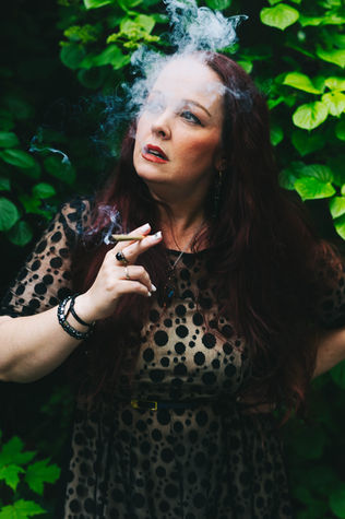 Abi Wright The Cannastrologer smoking joint in black dress