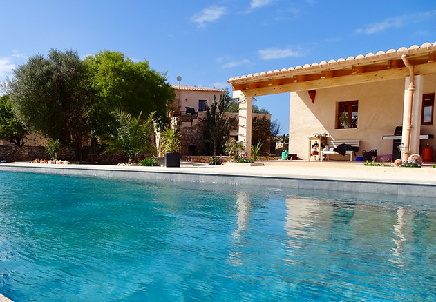 Ein blauer Pool vor einer alten mallorquinen Finca.