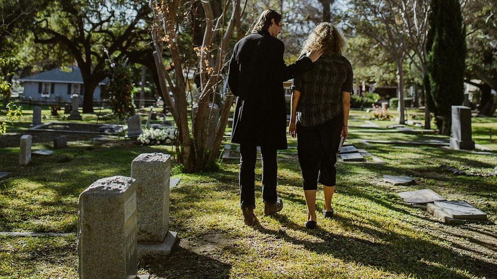 A sed couple leaving a gravestone