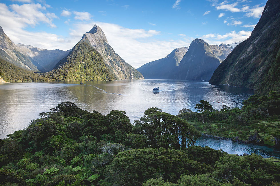 A boat returning through Milford Sound fjord with steep mountain cliffs rising on either side.