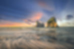Thumbnail: Sunset view of serene Wharariki Beach at Golden Bay, with large arch-shaped rock formations in the water.