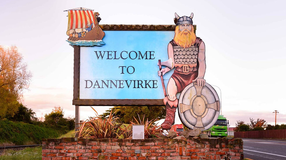 Thumbnail: Welcome sign for Dannevirke featuring a Viking holding a shield and axe, with a Viking ship above—a nod to the towns heritage