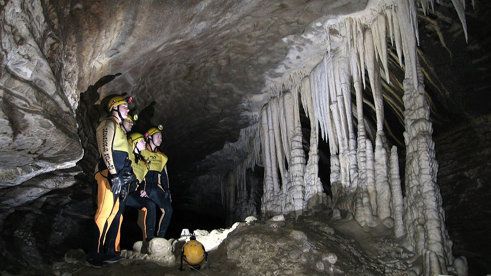 Thumbnail: Two individuals wearing yellow jackets stand at the entrance of a cave, ready to explore the dark interior.
