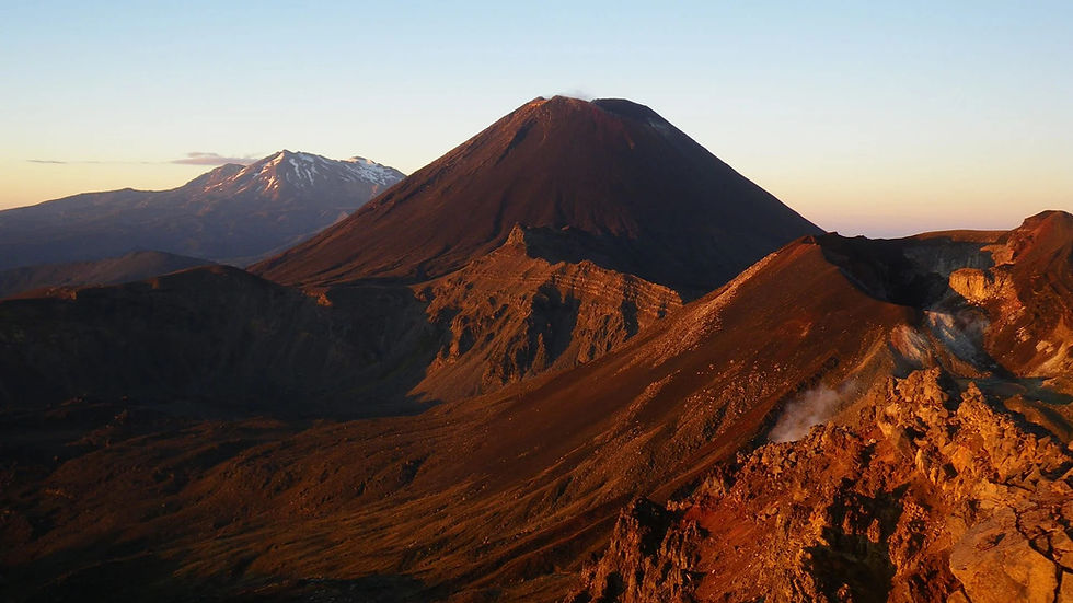 Thumbnail: A scenic view of Mount Ngauruhoe at sunset, featuring its dark, conical shape with another snow-capped peak in the background