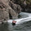 Thumbnail: A red speedboat with passengers zips through the narrow river canyon of Buller’s wilderness, carving a white wake in water.