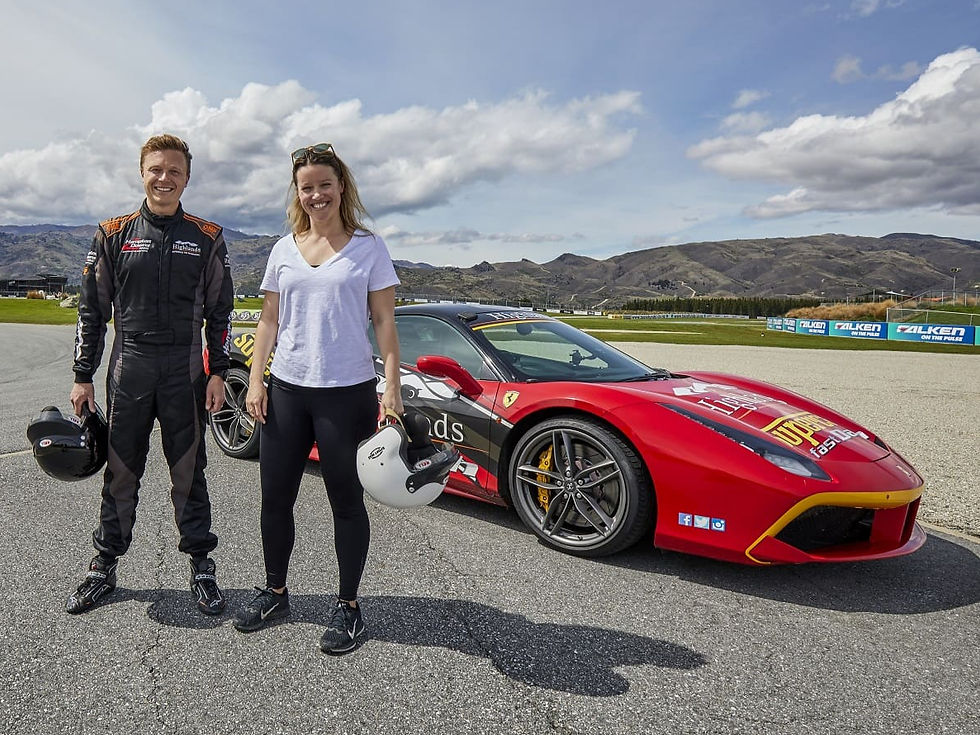 Thumbnail: Two people stand smiling next to a red sports car with racing decals on a track in Cromwell, Central Otago.