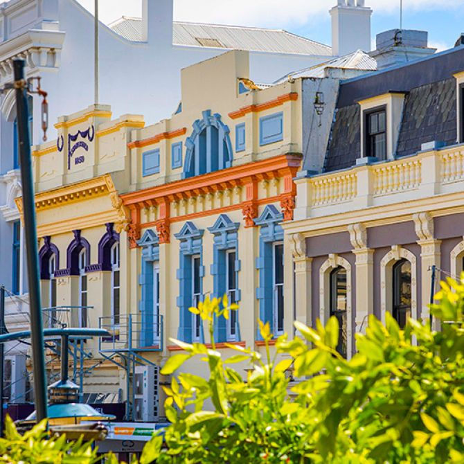Thumbnail: Colorful historic buildings with ornate facades in shades of yellow, orange, and purple line a street in Timaru.