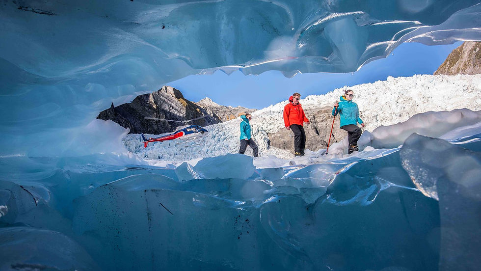 Thumbnail: Inside a blue ice cave in New Zealands Glacier Country, three people in vibrant outdoor gear traverse the Franz Josef Glacier