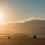 Thumbnail: A tranquil beach scene at sunset in Nelson, New Zealand, with the bright sun low in the sky casting a warm glow.