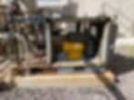 Industrial pump unit installed on a concrete base with surrounding piping.