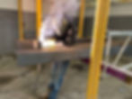 Welder working on a structural steel beam indoors.