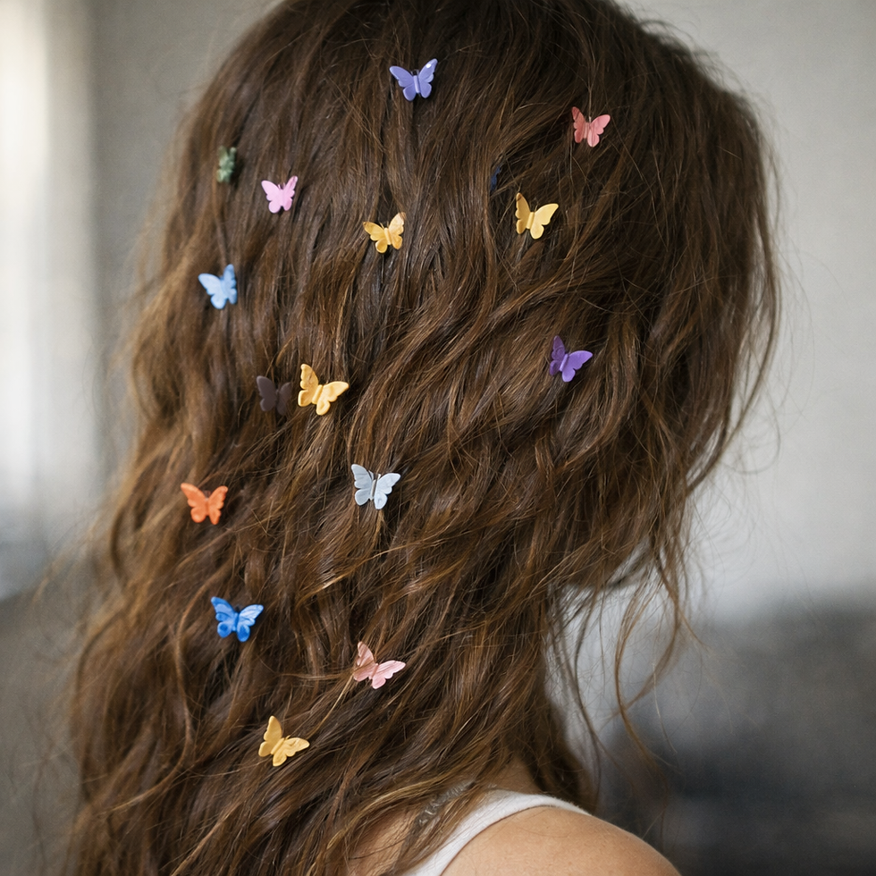 Brown wavy hair adorned with colorful butterfly clips in a soft-focus setting, creating a whimsical, playful mood.