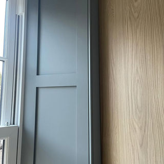 A gray sliding door with a modern panel design is partially open, revealing a light wood texture beside it