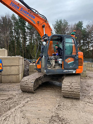 A construction worker is engaged in tasks at a construction site, with tools and materials visible around him.