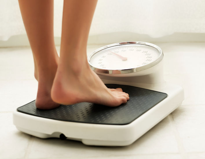 A woman stands on a scale