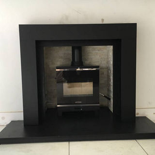 Modern fireplace with a sleek black frame, set against a white wall