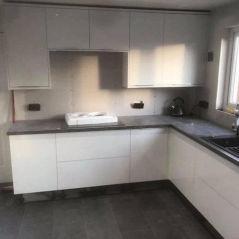 A kitchen with white cabinets featuring a stove, oven, and sink