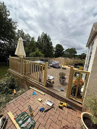 A wooden deck with a railing features patio furniture