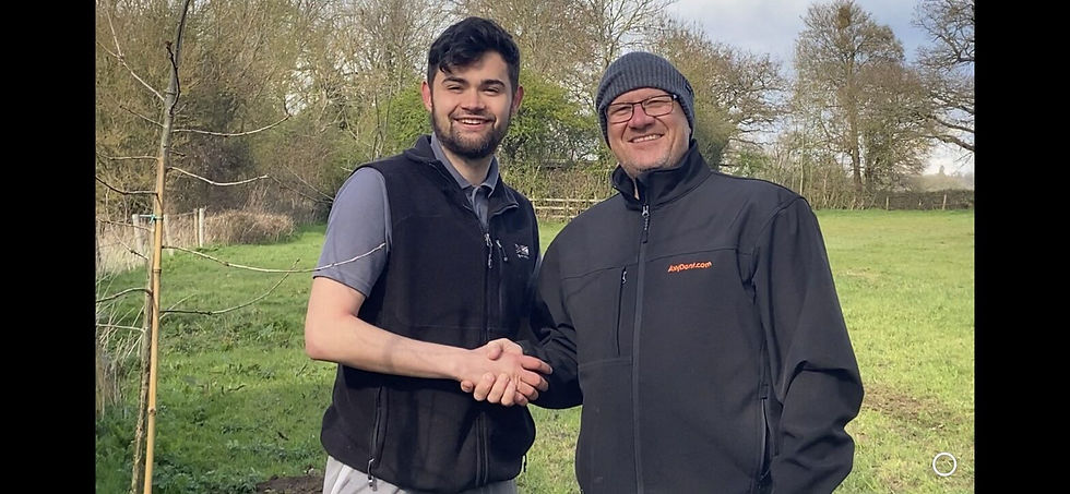 Two men shaking hands in front of a large green tree, symbolizing agreement and collaboration.