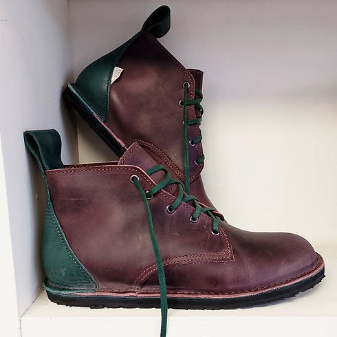 A pair of stylish high-top boots with maroon leather and green accents, including laces and heel.