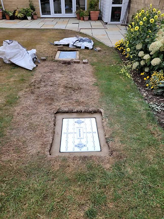 Two freshly laid concrete slabs, bordered by worn grass, lie parallel in a garden