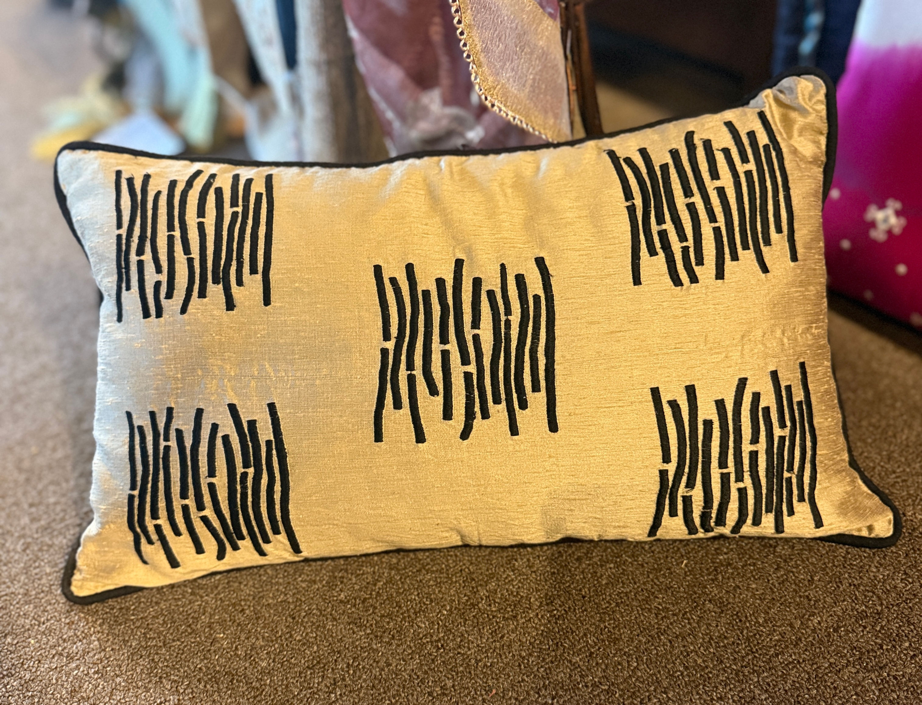 Gold rectangular cushion with black embroidered pattern