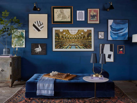 En stue med blå vegg med mange bilder på veggen