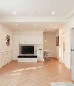 Pièce rénovée avec parquet en chevrons, murs blancs et finitions modernes dans un intérieur lumineux