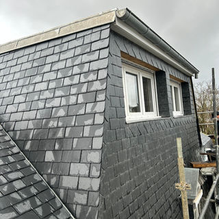 Détail toiture en ardoise avec gouttière zinc et finition en rive sur maison rénovée