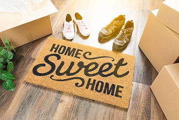 Home Sweet Home doormat with shoes and moving boxes.