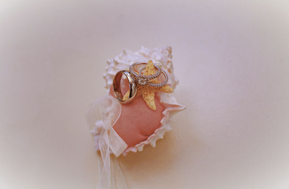 Close-up of wedding rings resting on a seashell in the sand on the beach in St. Croix, USVI during a destination beach wedding.