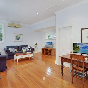 Bright living room with wooden floors, sofa, coffee table, and television