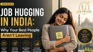 A professional woman embraces her laptop in a modern Indian workplace, symbolizing job satisfaction and employee retention, with the headline “Job Hugging in India: Why Your Best People Aren’t Leaving” and Ustride Corporate Training and Image Consultancy branding.