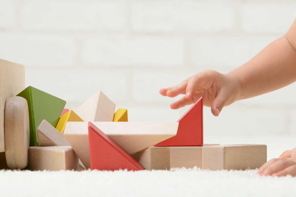 Child hand reaching for building block