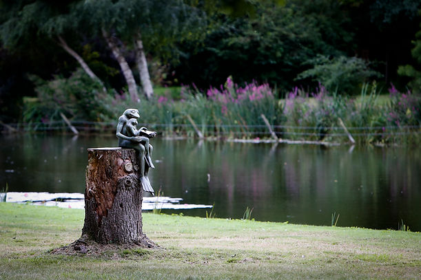 Statue of frogs sitting on a log by the lake