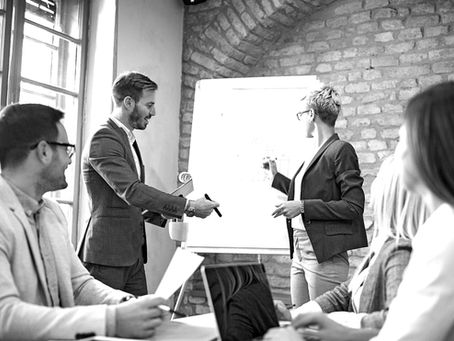 Ein Mann und eine Frau stehen vor einem Whiteboard.