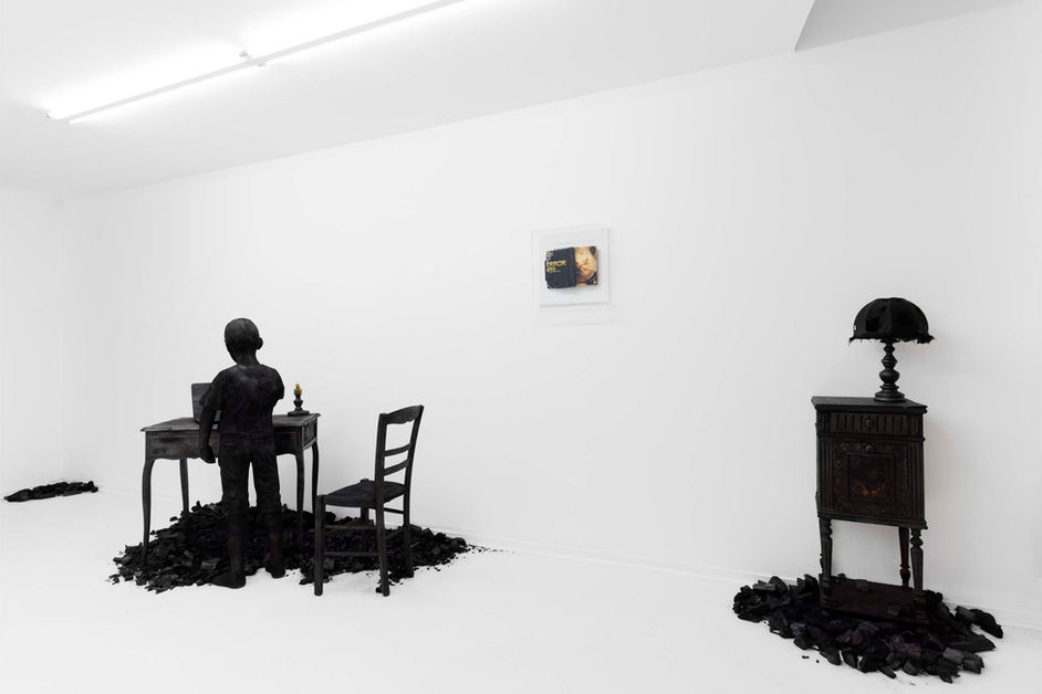 Installation artistique en galerie d'une sculpture en bois brulé sur le thème de la dépendance au numérique.