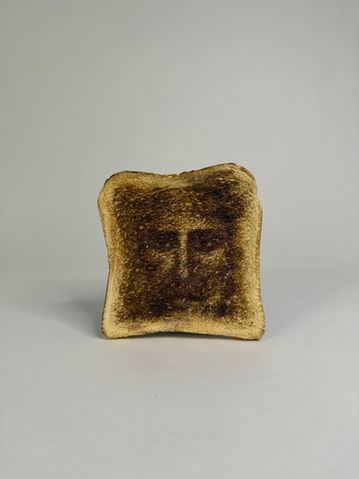 Art contemporain, sculpture d'une tranche de pain sur laquelle semble apparaitre le visage de jésus.