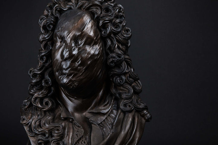 Sculpture en plâtre patiné noir d'un buste classique sur pied d'un homme dont le visage semble s'effacer.