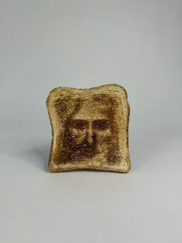 Art contemporain, sculpture d'une tranche de pain sur laquelle semble apparaitre le visage de jésus.