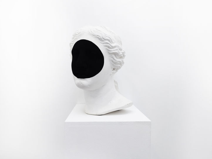Sculpture en plâtre d'un buste femme sur lequel un rond  de peinture ultra noire cachent les yeux et rend le visage non identifiable.