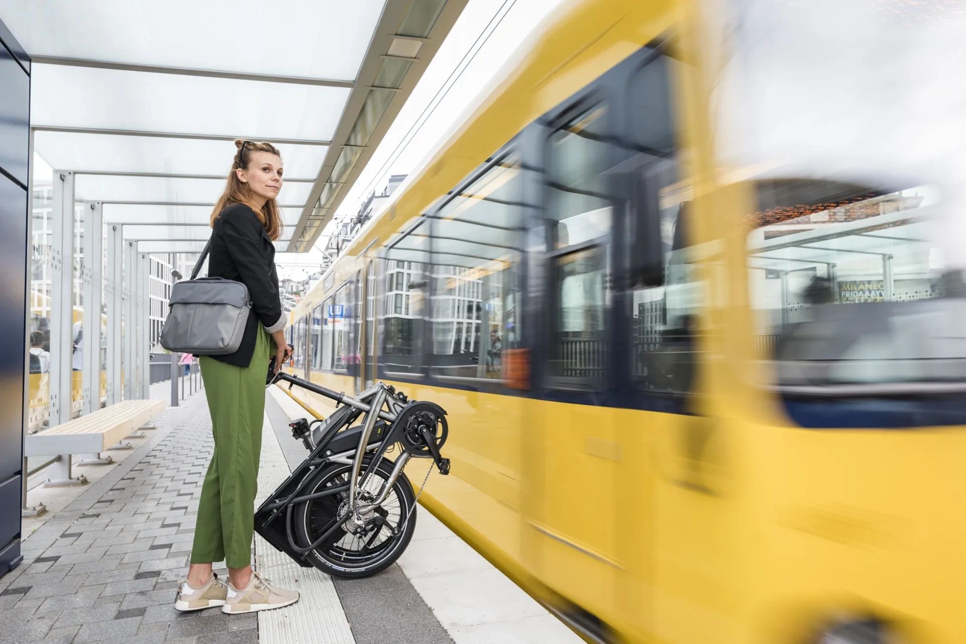 Woman waiting with her portable e-bike. Time is important so she has booked an appointment.