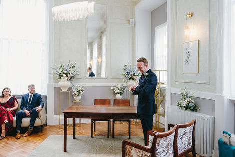 Groom waiting for the bride in the ceremony room at Chelsea Old Town Hall, London.