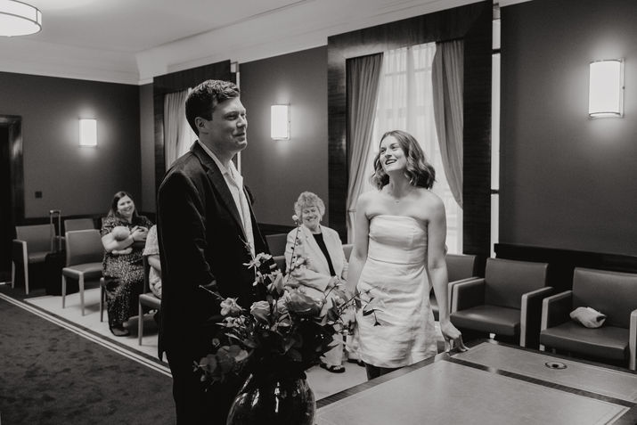 Bride looking at groom while standing together in front of the registrar table at Hackney Town Hall.