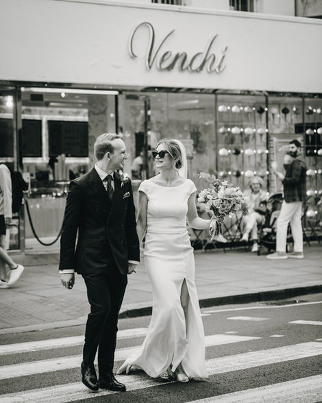 Just married couple crossing a pedestrian crossing with a Venchi store in the background in Chelsea, London.
